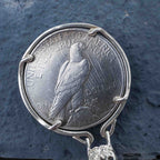Skull aviator coin pendant reversed to show the Peace Dollar standing eagle with United States of America and One Dollar inscription, in a four-prong bezel