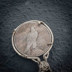 Medusa coin pendant reversed to show the Peace Dollar standing eagle with United States of America and One Dollar inscription, in a four-prong bezel