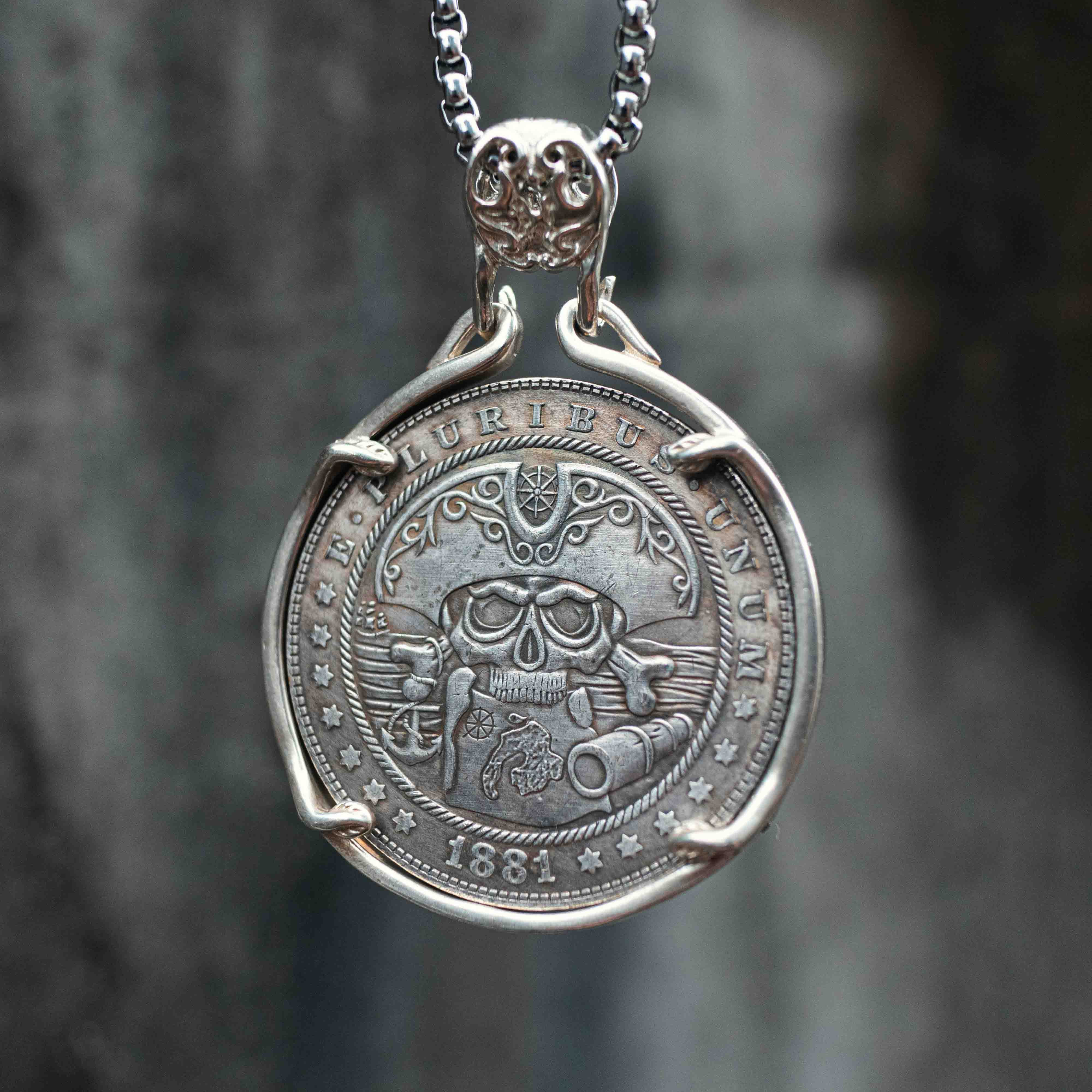 Pirate skull and crossbones coin pendant dated 1881 with rope border and star details, set in a four-prong bezel with skull bail on a box chain Main image