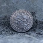 Close-up of a coin engraved with a pirate skull and crossbones, rope border, star details, E Pluribus Unum inscription, dated 1881