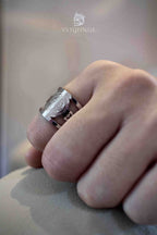Saint Benedict ring viewed from above on a loosely clenched hand, polished silver cutout band with the medal centered on top