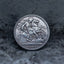 Close-up of a coin engraved with Saint George on a rearing horse driving a lance into a dragon below, dated 1900, on dark stone surface