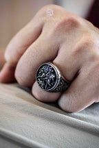 Saint George slaying the dragon engraved on an oxidized signet ring, worn on a clenched fist — medieval knight ring close-up