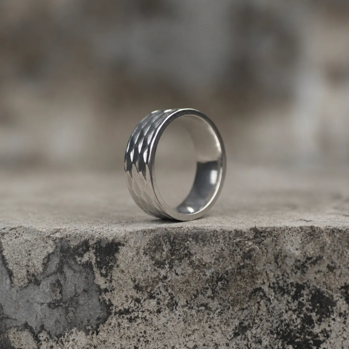 Side view of a silver-tone geometric faceted wide band ring