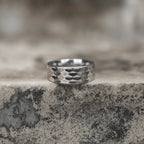 Silver-tone wide band ring with a repeating geometric faceted pattern