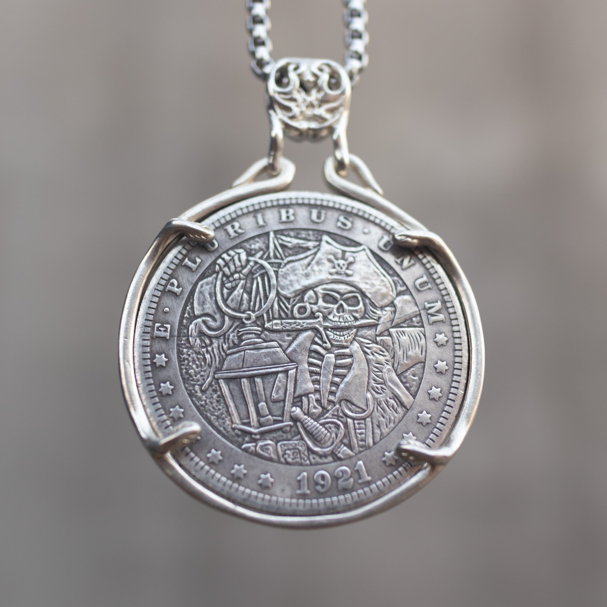 Coin pendant engraved with a skeleton pirate captain holding a lantern beside a ship sail, dated 1921, set in a four-prong bezel on a box chain Main image