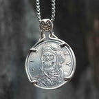 Coin pendant engraved with a skull wearing aviator goggles and flight helmet, Liberty inscription, set in a four-prong bezel with skull bail on a box chain