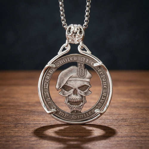 death smiles at everyone skull coin pendant necklace — military beret skull relief, gothic script inscription coin frame, skull bail, antique silver tone, dark wood surface