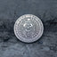 Close-up of a coin engraved with a skull in a feathered war bonnet, ring of small skulls as border decoration, E Pluribus Unum outer edge, dated 1883, on dark stone