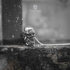 skull heart pendant resting against metal railing — dark street aesthetic lifestyle shot with oxidized silver finish