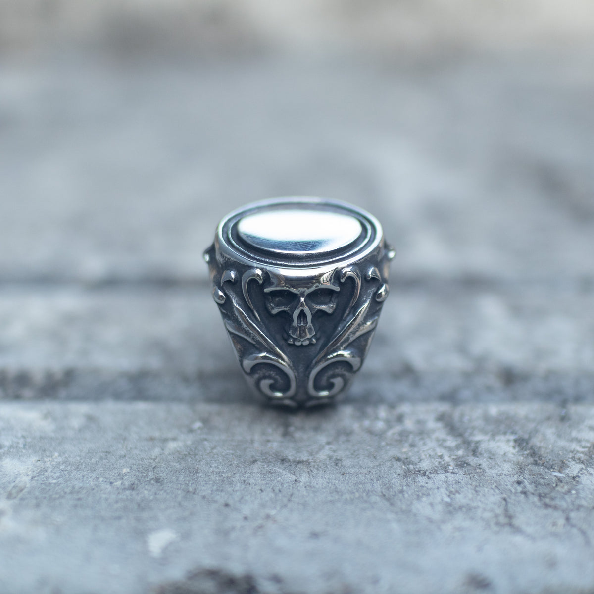 Oval mirror face and skull detailing on the silver-tone signet ring
