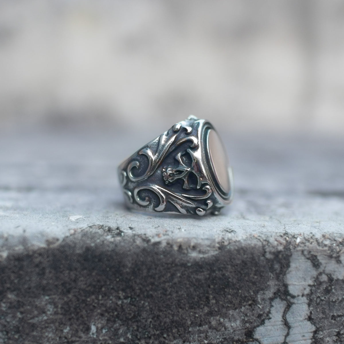 Skull mirror signet ring with ornate scrollwork, shown from the side