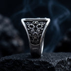 Full front view of tapered gothic signet ring — skull flanked by curling octopus tentacles on trapezoidal face, polished silver band, dark atmospheric smoke background