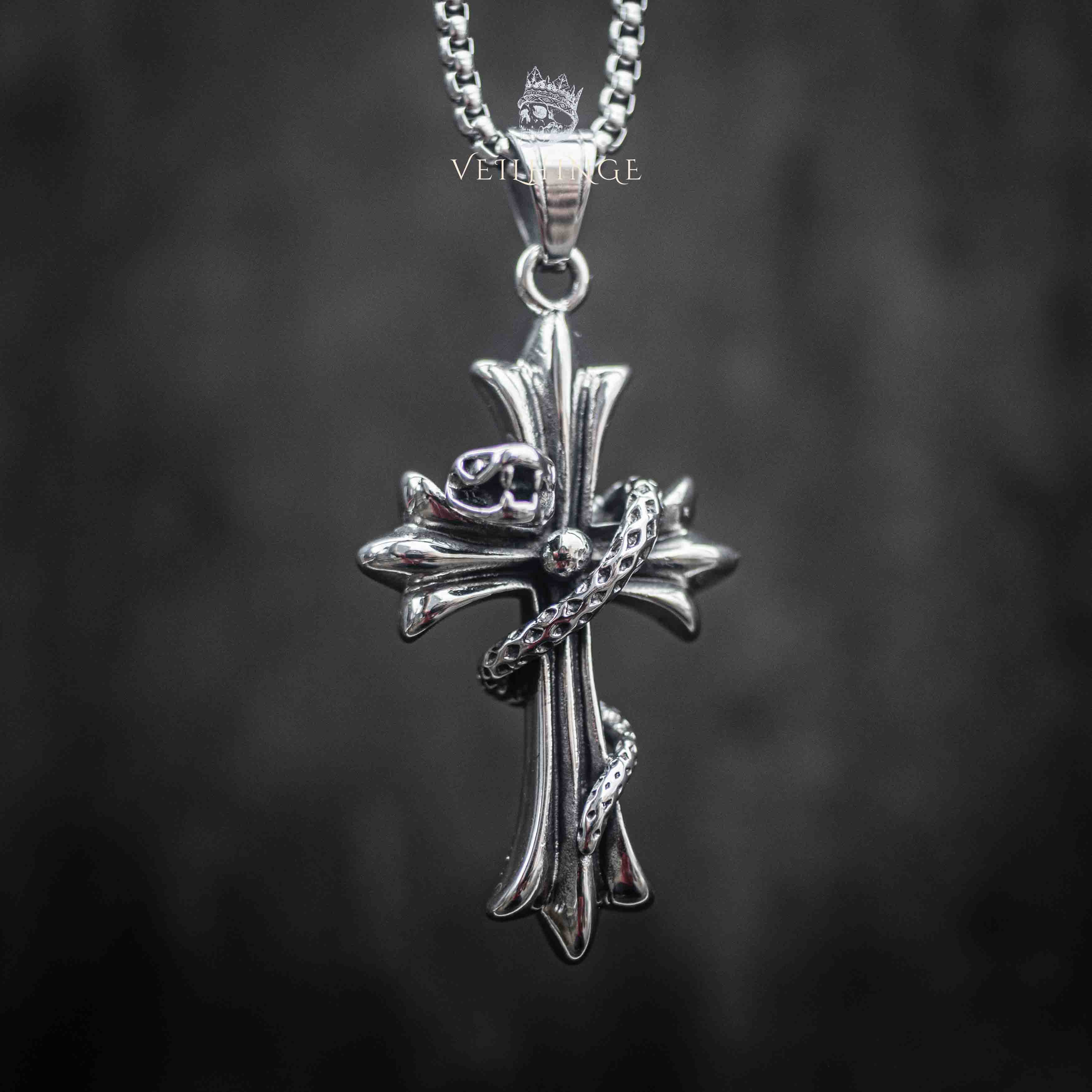 snake wrapped cross pendant front view — serpent head resting at center cross with oxidized dark metal finish Main image