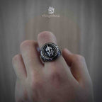 Spartan helmet signet ring with circular inscription worn on a clenched fist, oxidized silver championship-style ring with crossed spears on the face