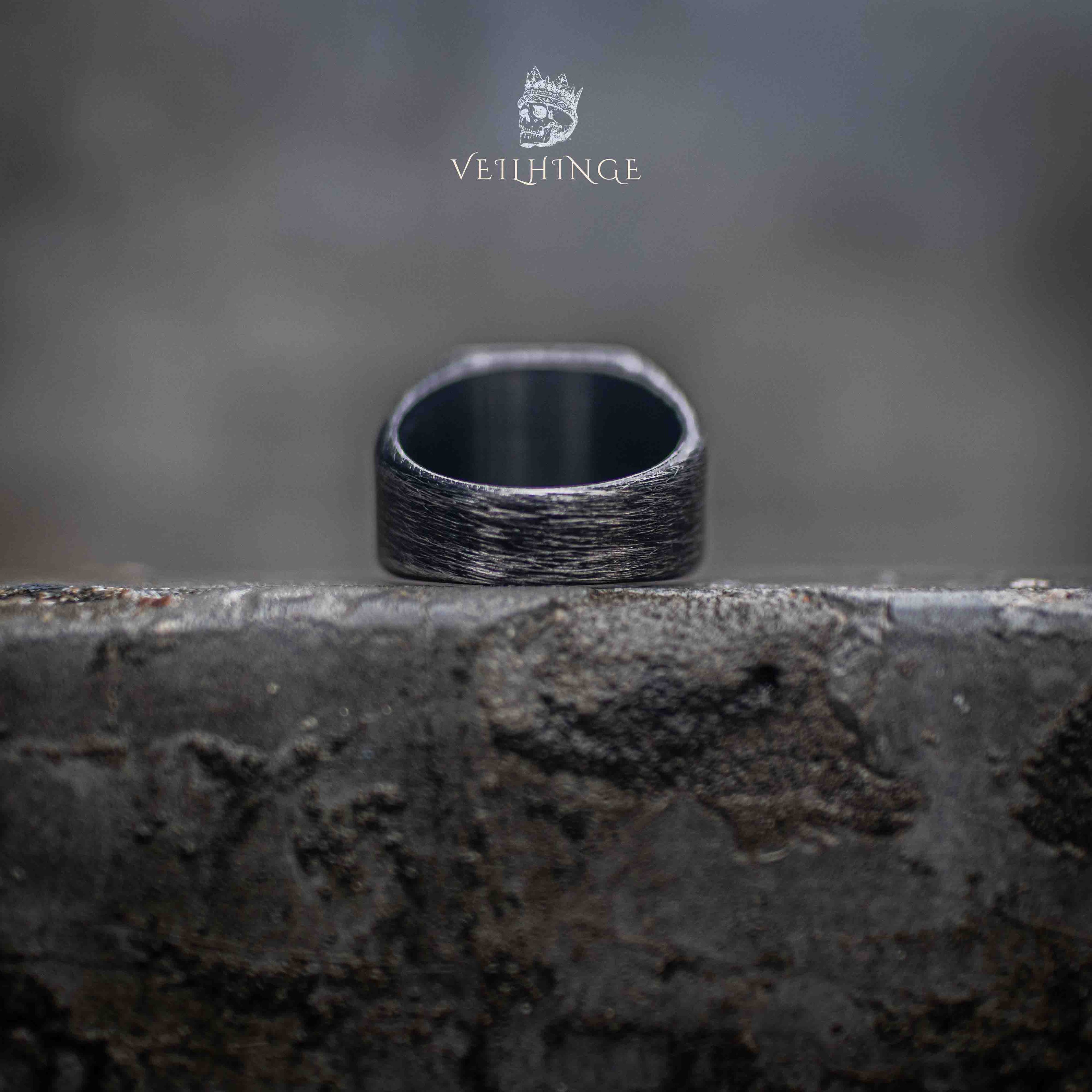interior view of oxidized square signet ring — smooth inner band contrasting with brushed outer face on stone surface
