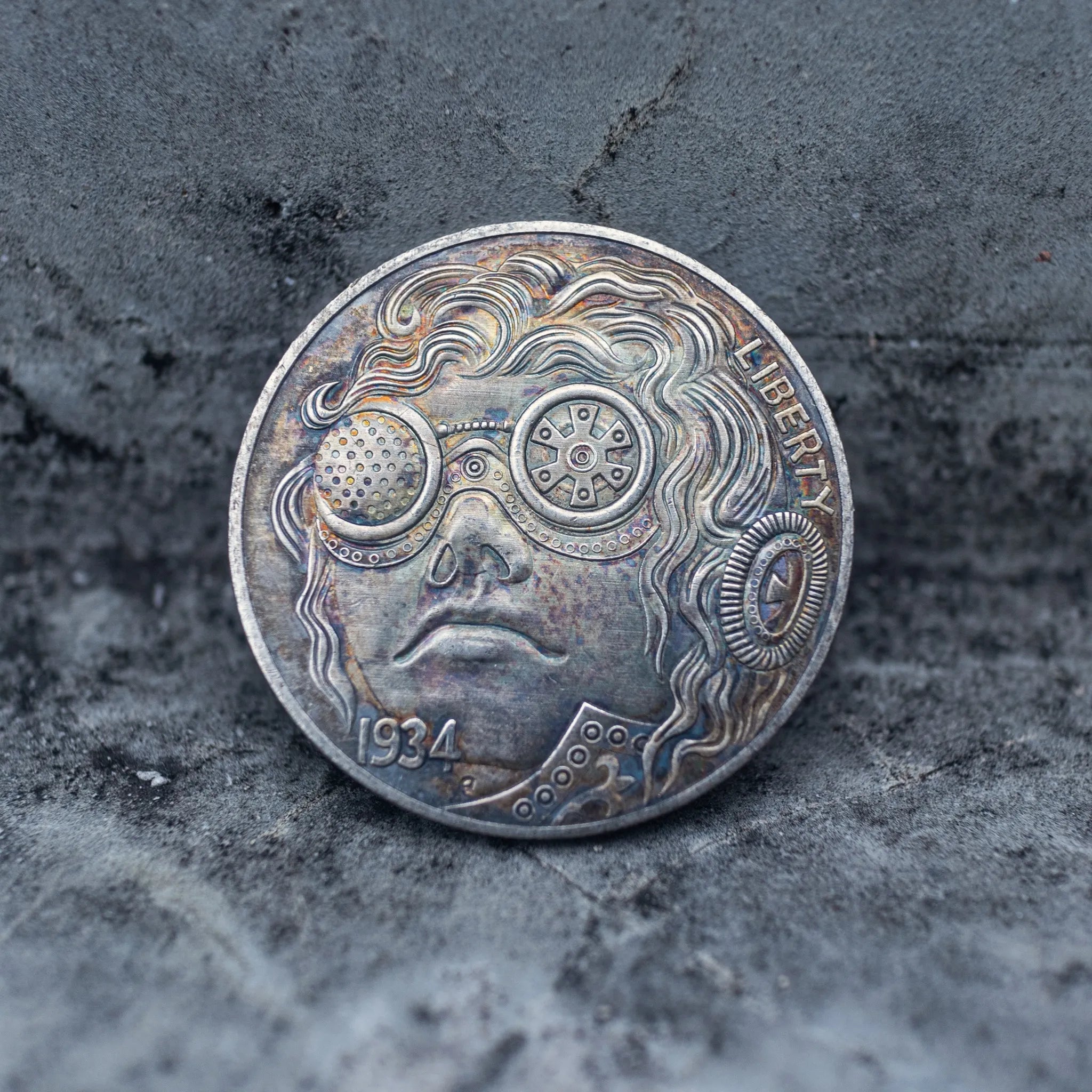 Close-up of a coin engraved with a steampunk character in mechanical round goggles with gear patterns, flowing curly hair, rivet dot details below, Liberty inscription, dated 1934