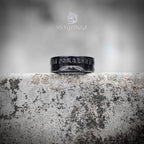 Angled view of black oxidized Soviet coin ring showing partial Cyrillic anniversary text — worn-in dark finish, historical relic aesthetic on weathered stone