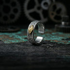 Veilhinge Gothic Eye Ring with gold eye symbol and intricate silver carvings on dark wooden background