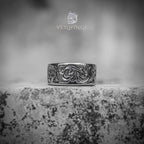 Wide band ring with continuous Victorian floral scroll engraving — oxidized silver finish, acanthus leaf pattern wrapping the full band