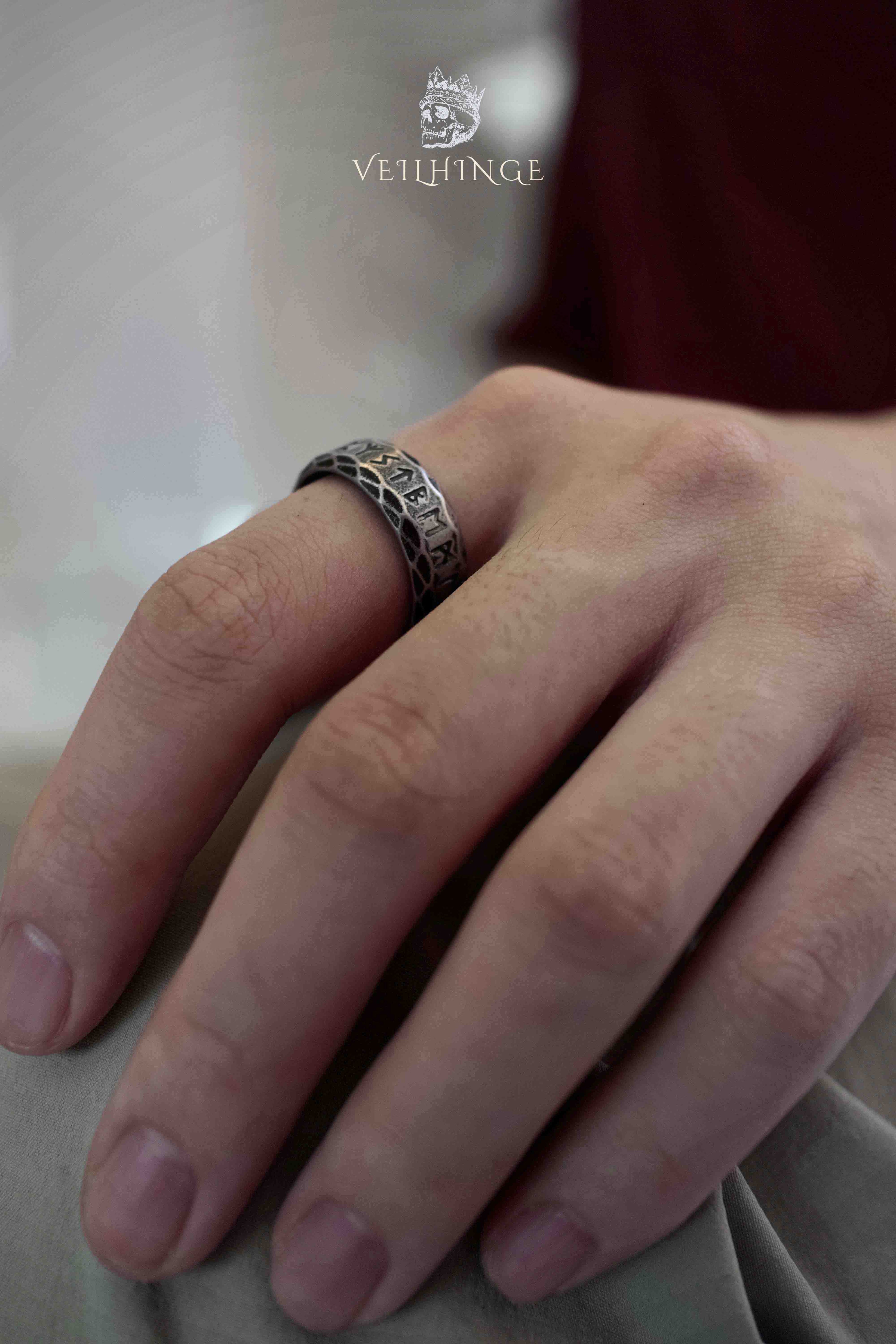 Viking rune band ring with Celtic knotwork lattice worn on a hand, dark oxidized finish showing the full ring width and proportion on the finger