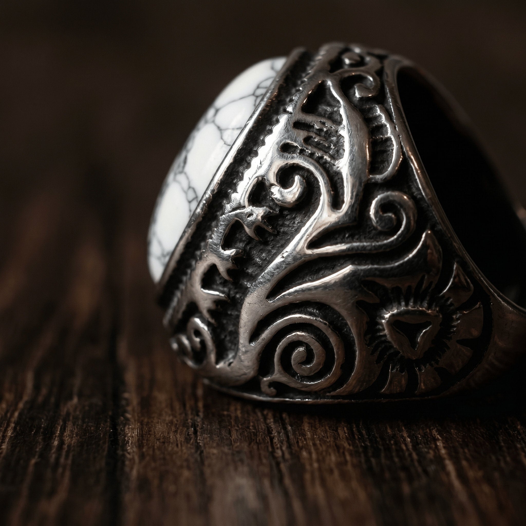 close-up detail of engraved gothic signet ring with white stone
