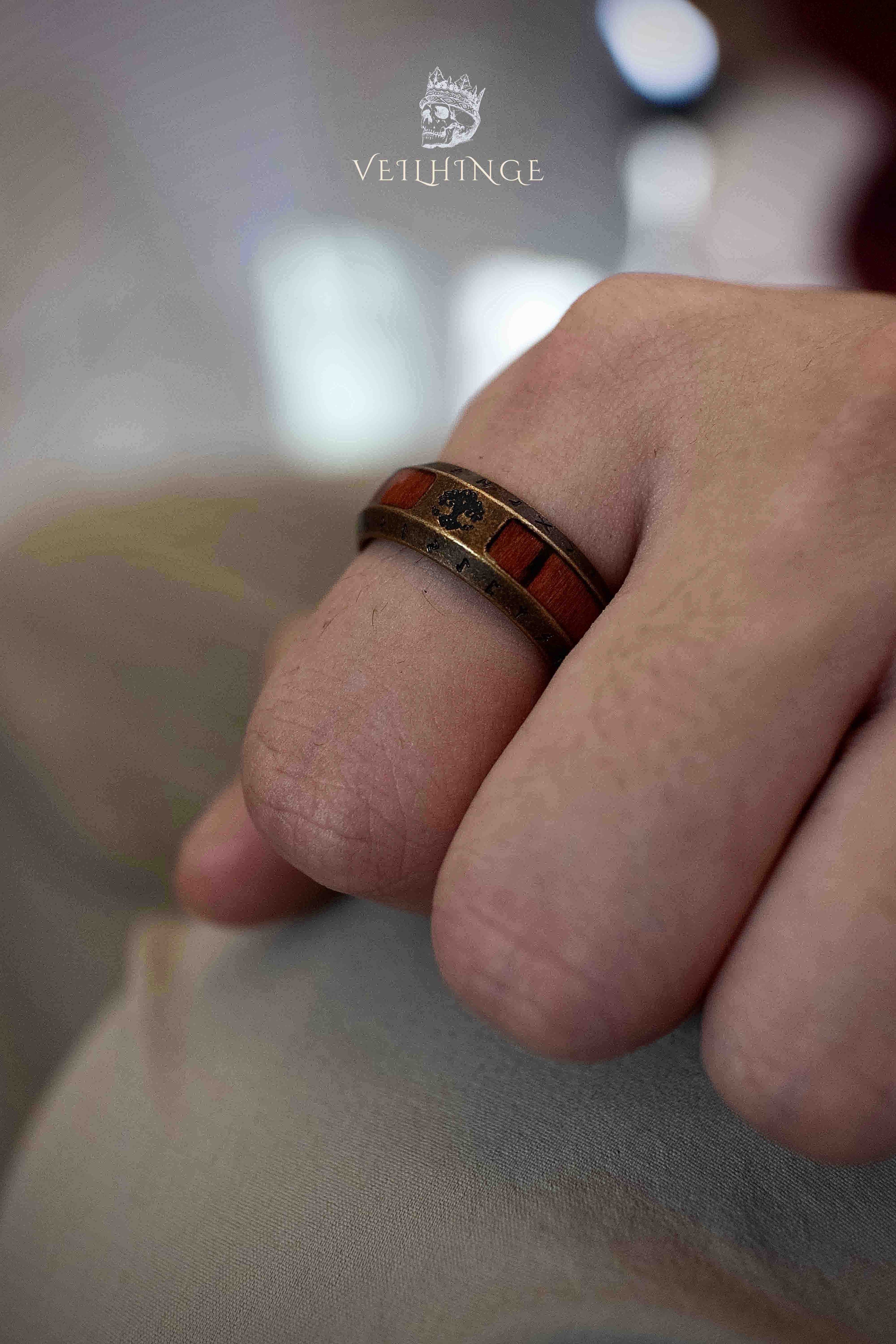 Side profile of a Norse rune ring with a warm wood inlay band set in a bronze metal frame, runic border visible along both edges of the ring
