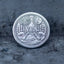 Close-up of the NO face of a decision coin engraved with a winged skeleton above a heart with NO inscription and anchor symbol below