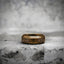 Antique gold Viking ring resting on a stone surface, engraved with a Yggdrasil tree of life and Celtic knotwork pattern along the band

